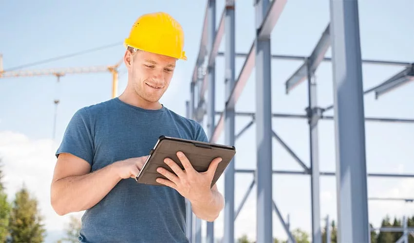 Bauarbeiter schaut auf sein Tablet auf der Baustelle