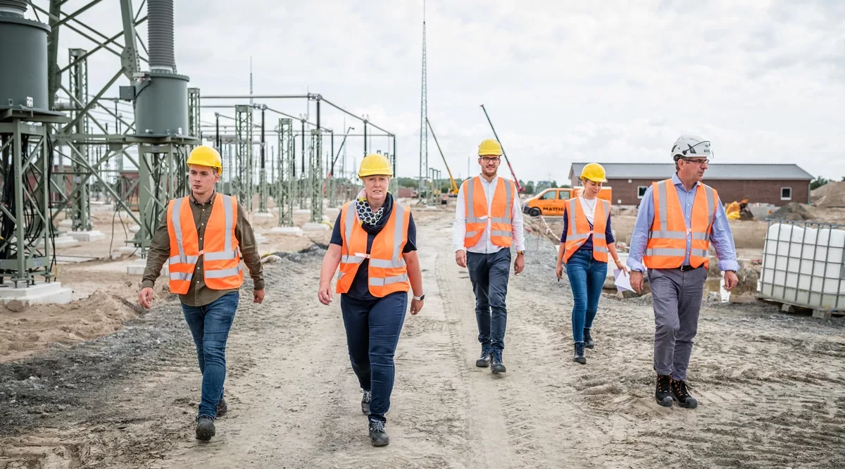 Mitarbeiter der Matthäi- Gruppe gehen mit Warnweste und Schutzhelm über eine Baustelle